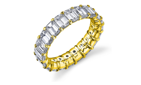 A yellow gold eternity wedding band adorned emerald cut diamonds, available at Kirk Bridal.
