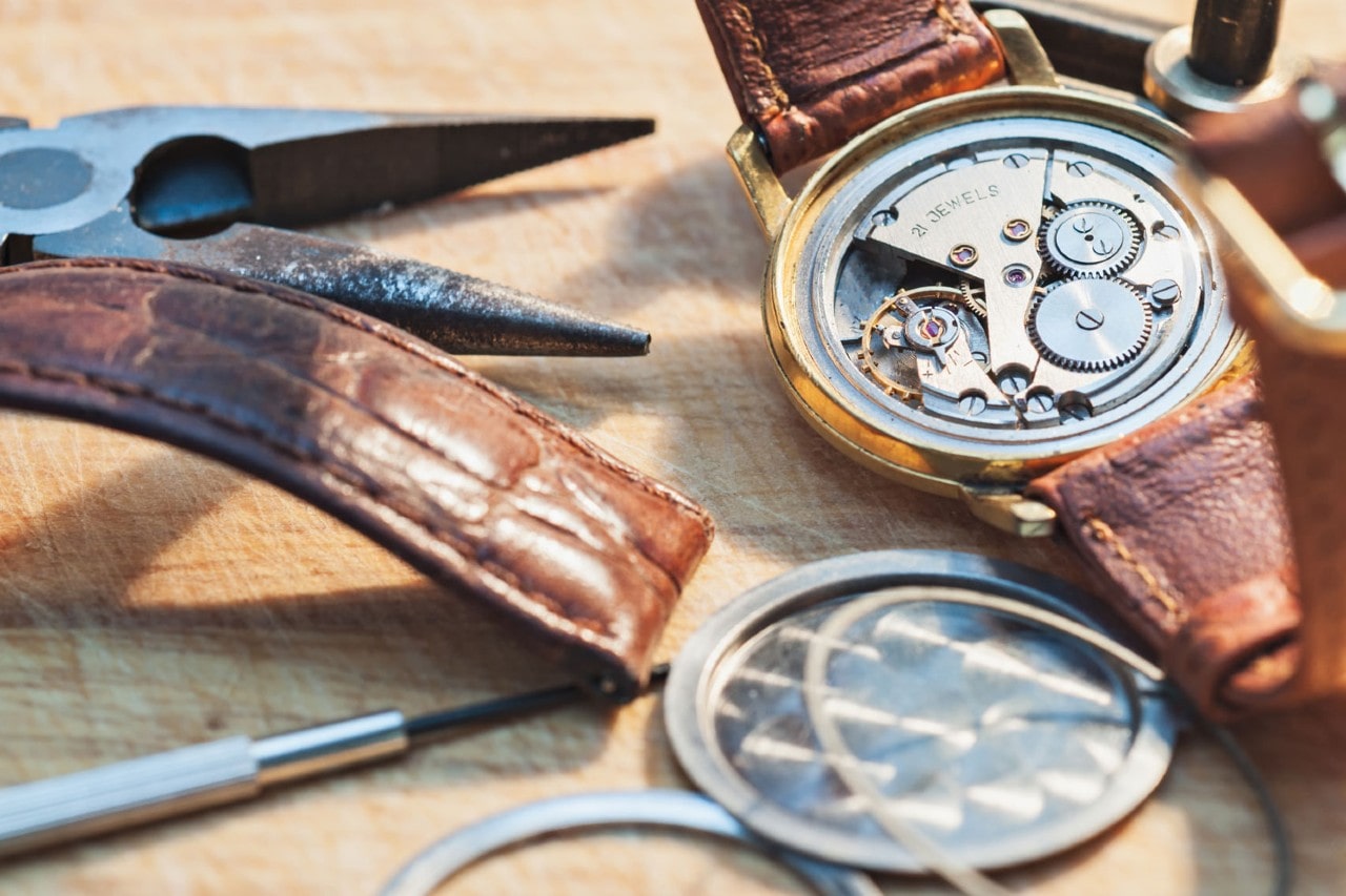 A close-up of luxury wristwatches with leather straps resting on a rustic wooden surface, showcasing their textures.