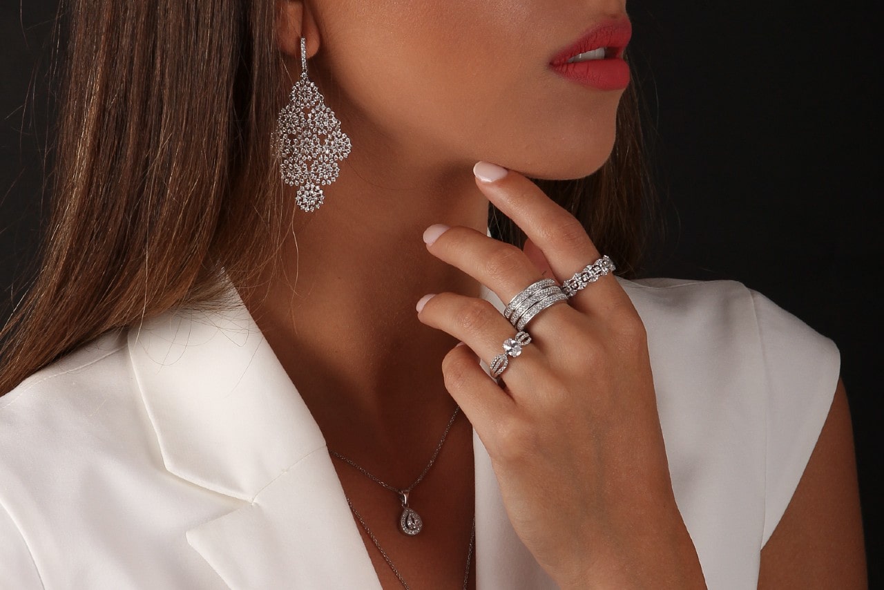 a lady wearing diamond fashion rings, necklace, and earrings
