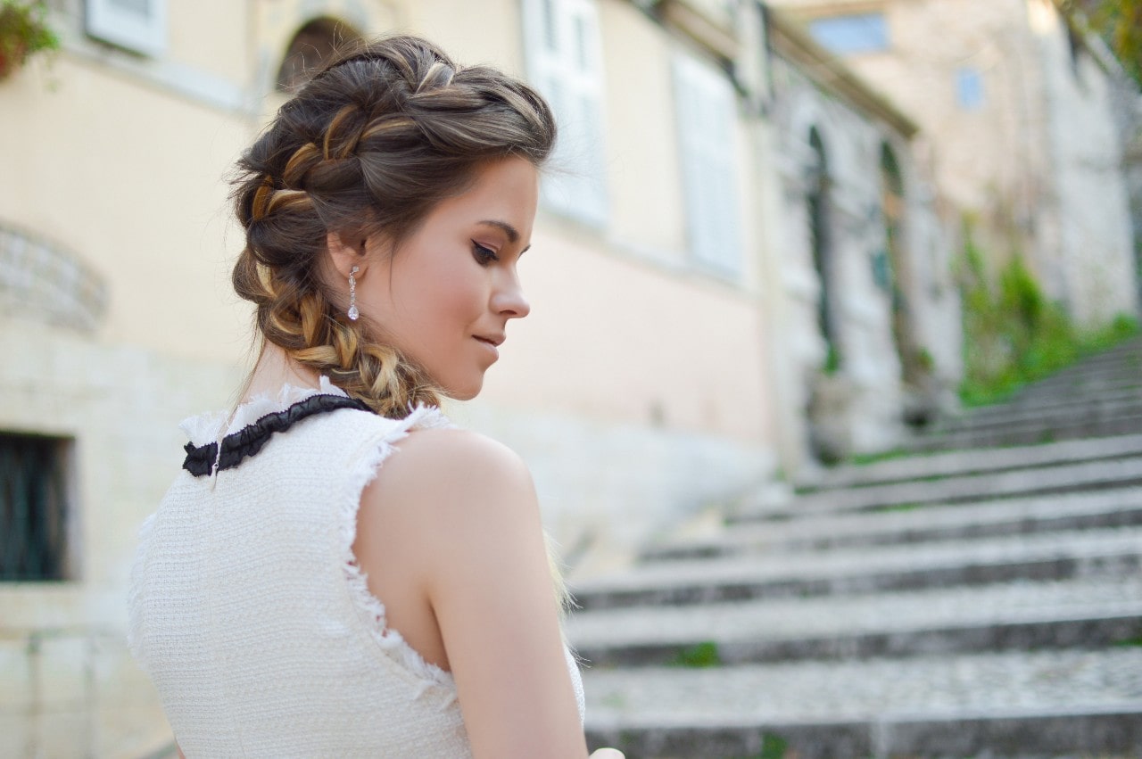 A fashionable woman wears diamond drop earrings while walking through the city.