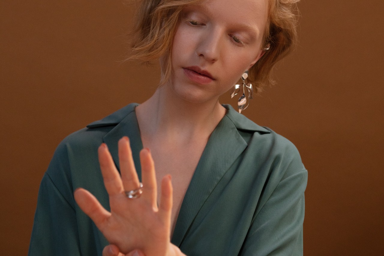 a red-haired woman inspects her rings while sitting in an office.
