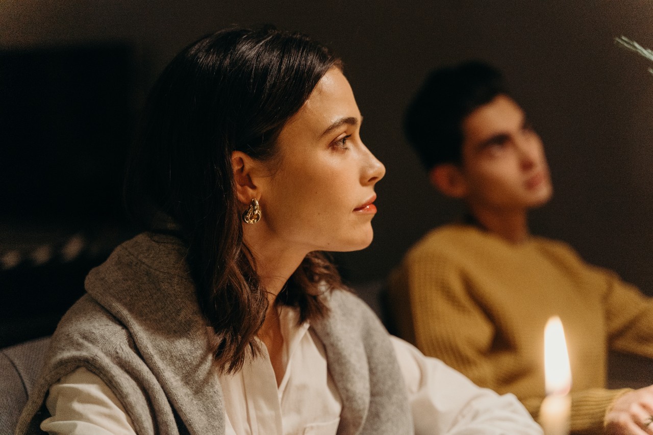A young woman wearing chunky chain hoop earrings listens to a lecture in a college classroom.