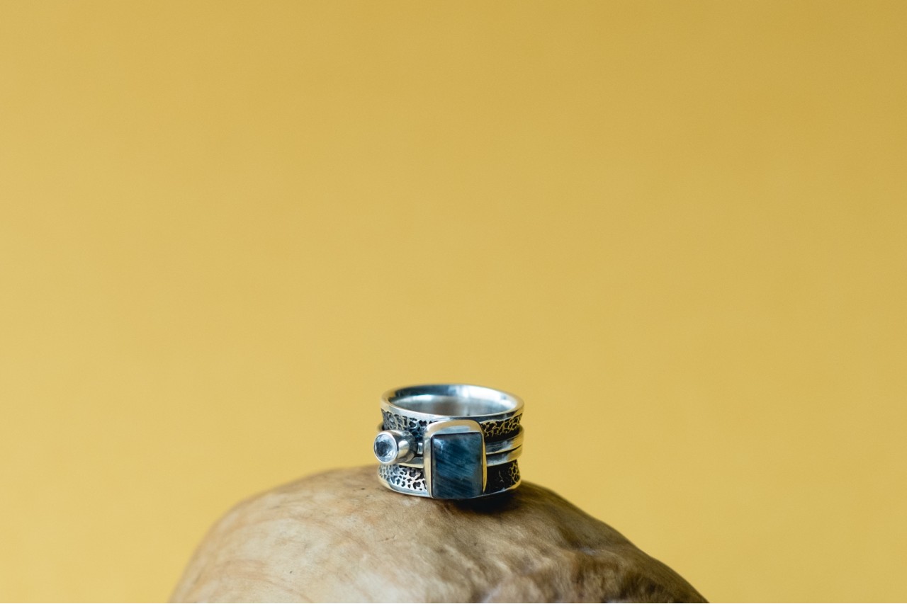 a large silver ring fitted with two blue gemstones and featuring textured metalwork