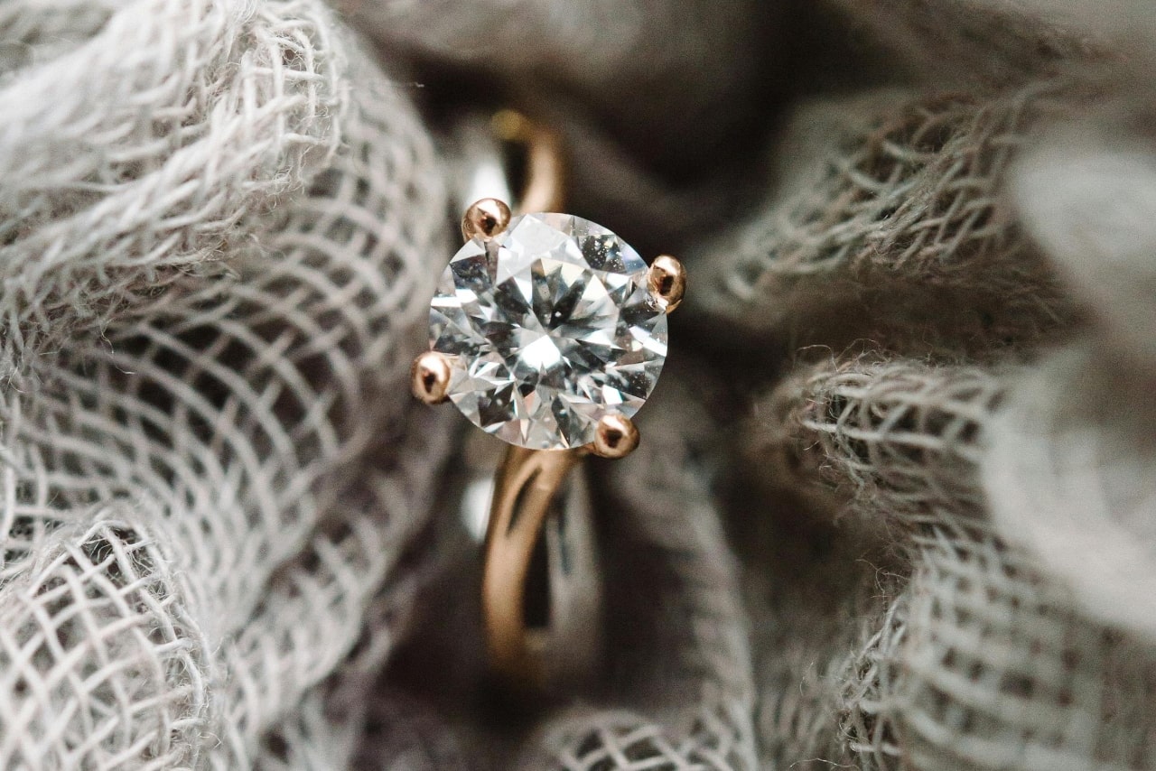 A yellow gold solitaire round cut engagement ring inside the grey fabric