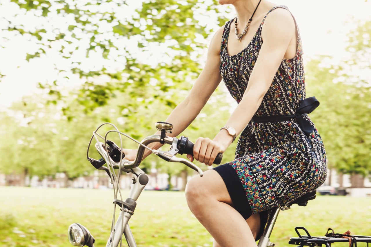 Woman biking in a spring dress and a watch in a park