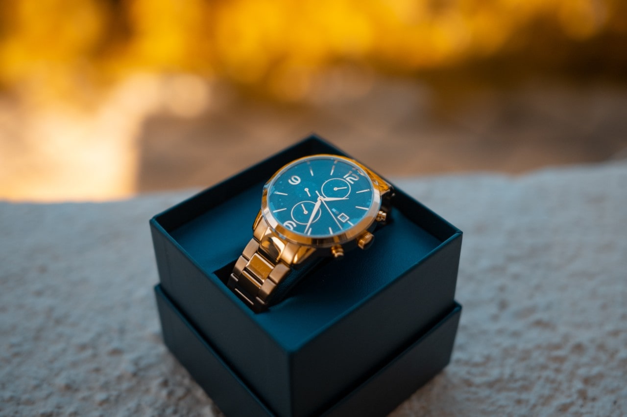 A gold watch in an open black gift box