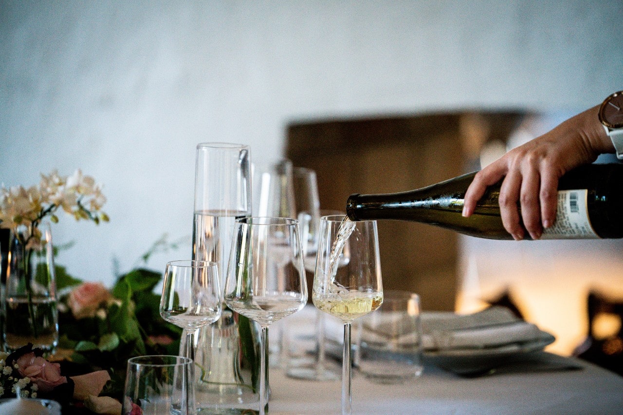 A woman pours a glass of champagne at the Thanksgiving dinner table.