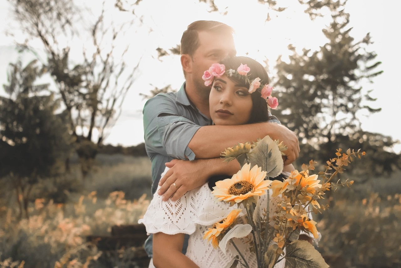 a bride and groom embracing in the outdoors