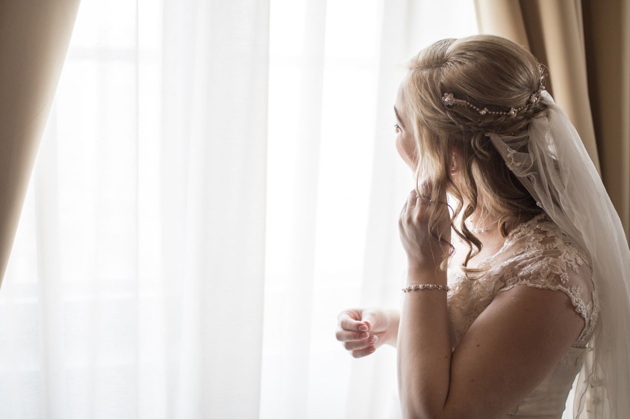 a bride getting ready on her wedding day, putting on earrings