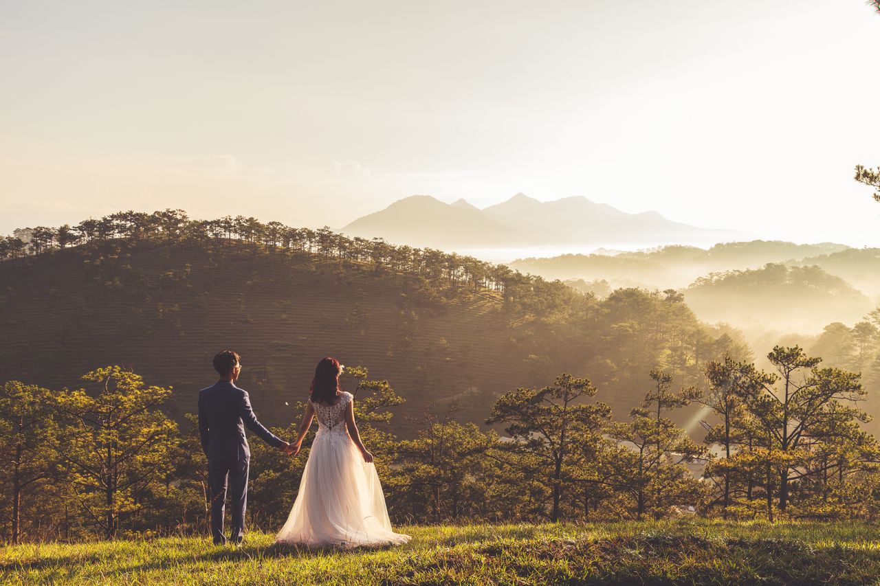 a bride and groom standing on a hill looking out over the scenery