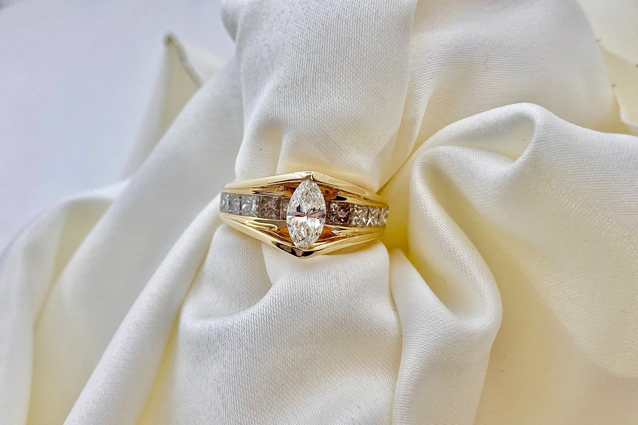 a yellow gold and diamond engagement ring with a cloth threaded through it