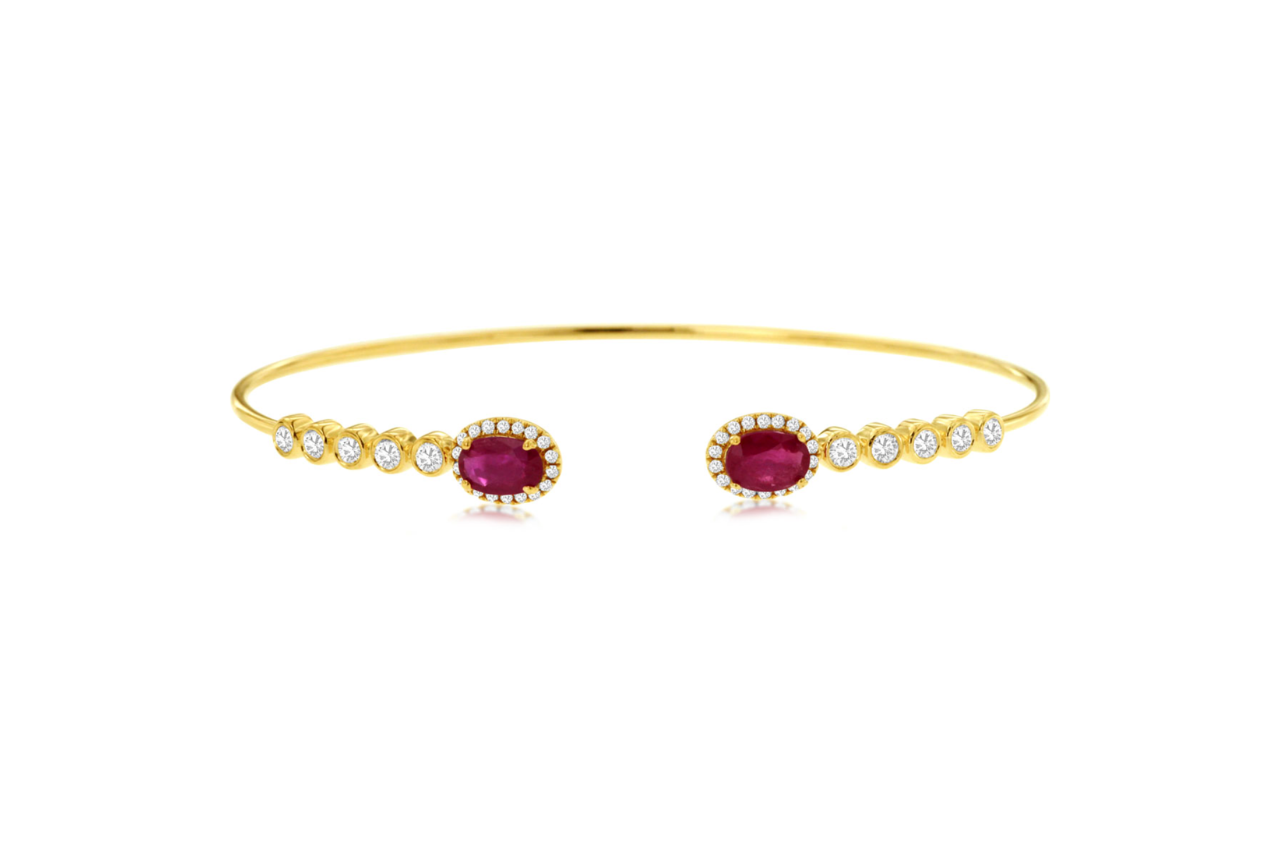 A yellow gold bangle with ruby gemstones and diamond accents.