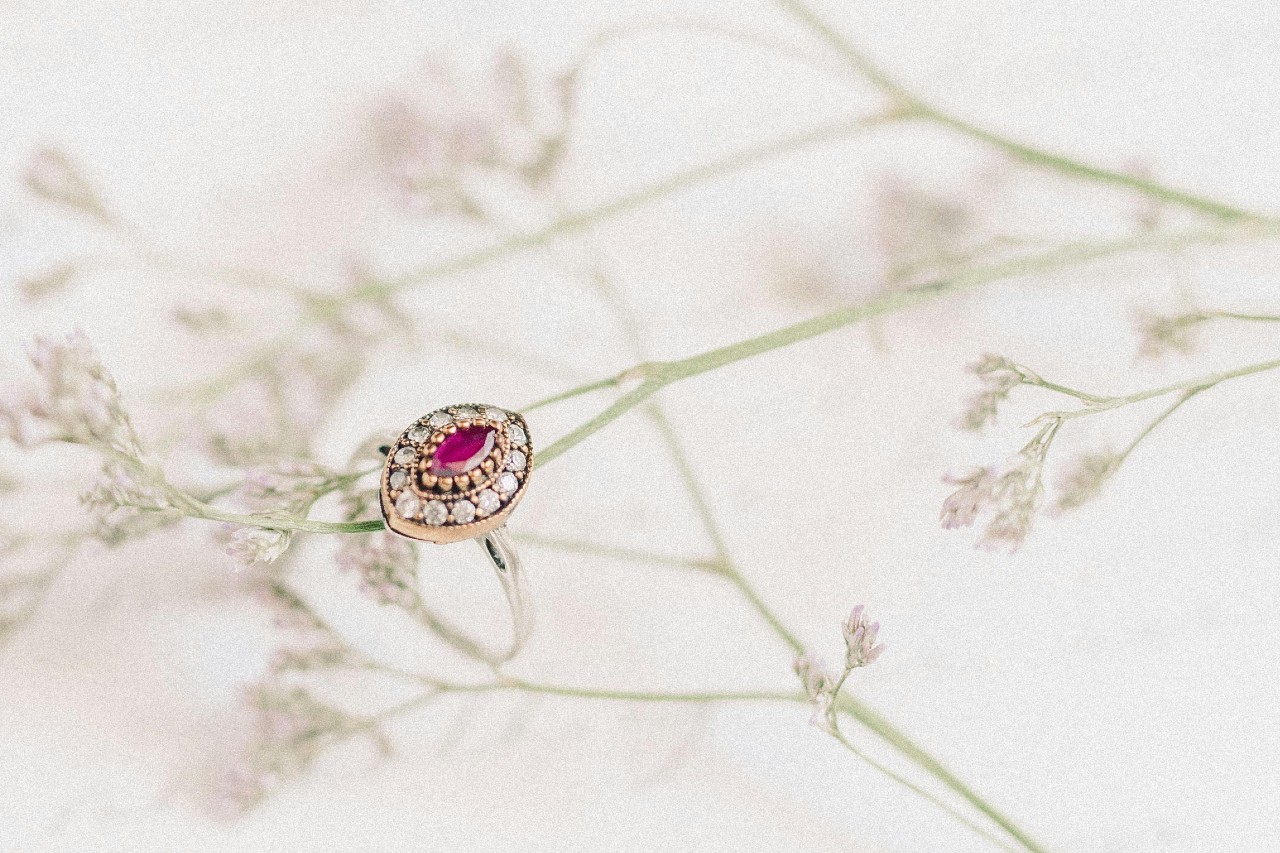 Vintage-style ruby and diamond ring resting on delicate baby's breath flowers.