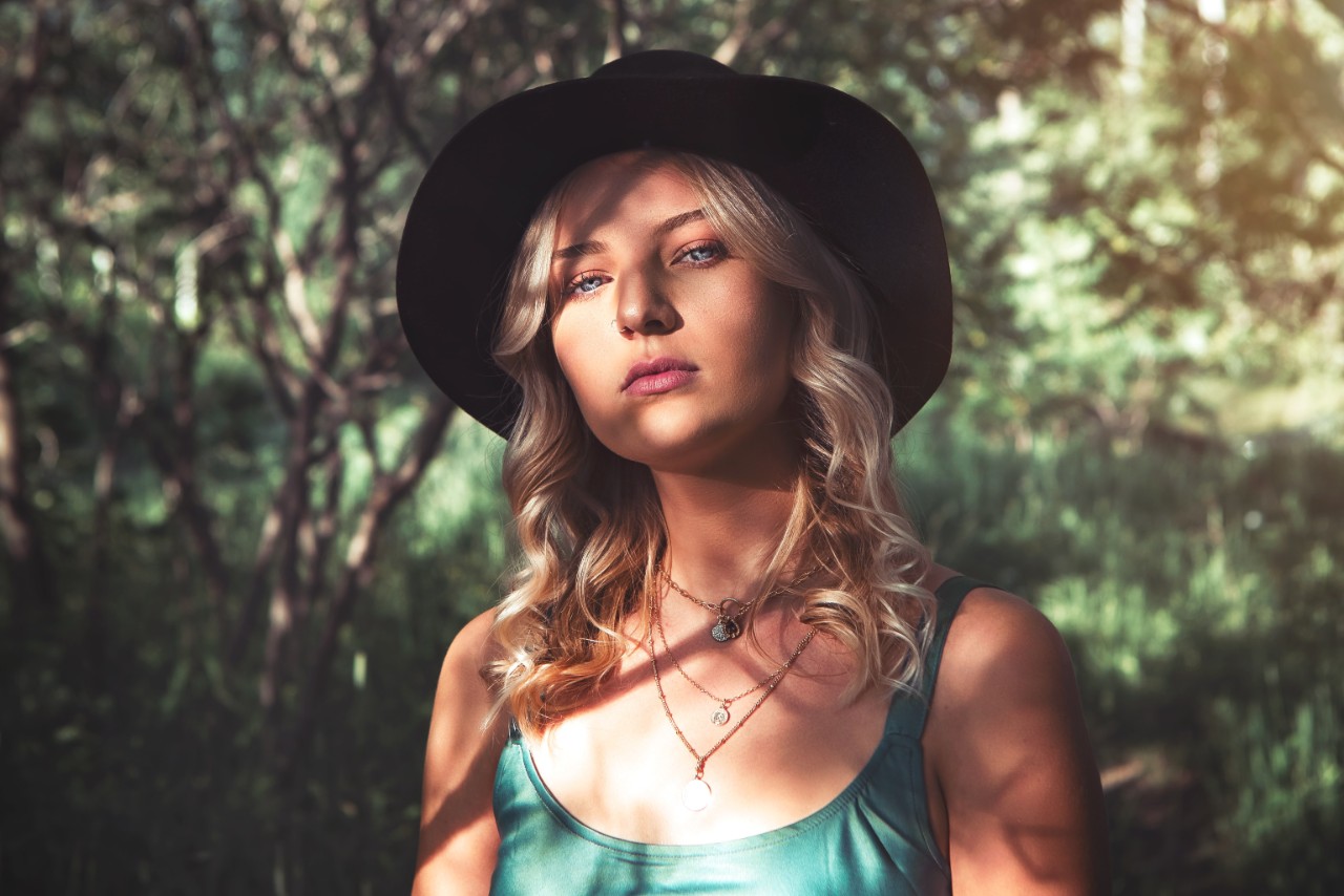 Fashionable blond lady with a sunhat and three eye-catching necklaces.