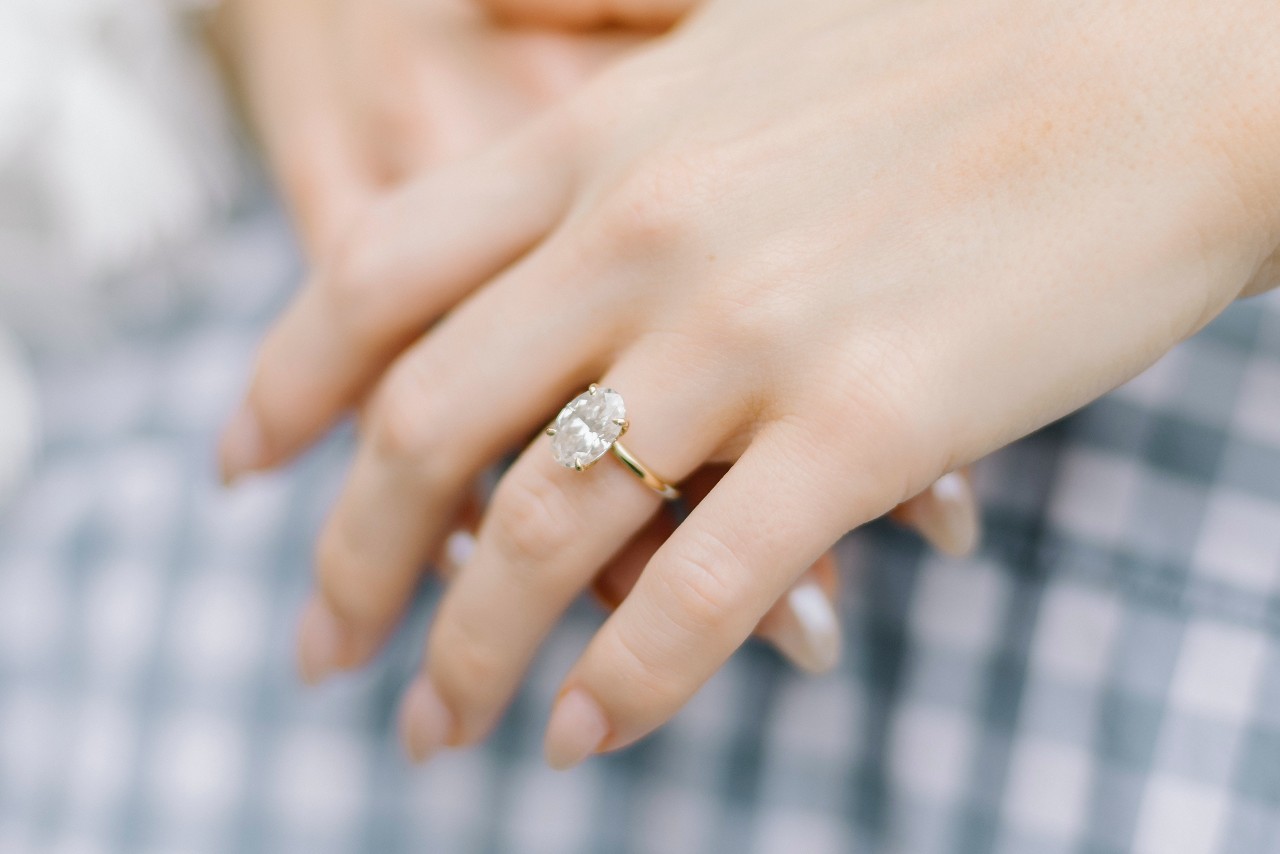 a woman’s hand wearing an oval cut engagement ring.
