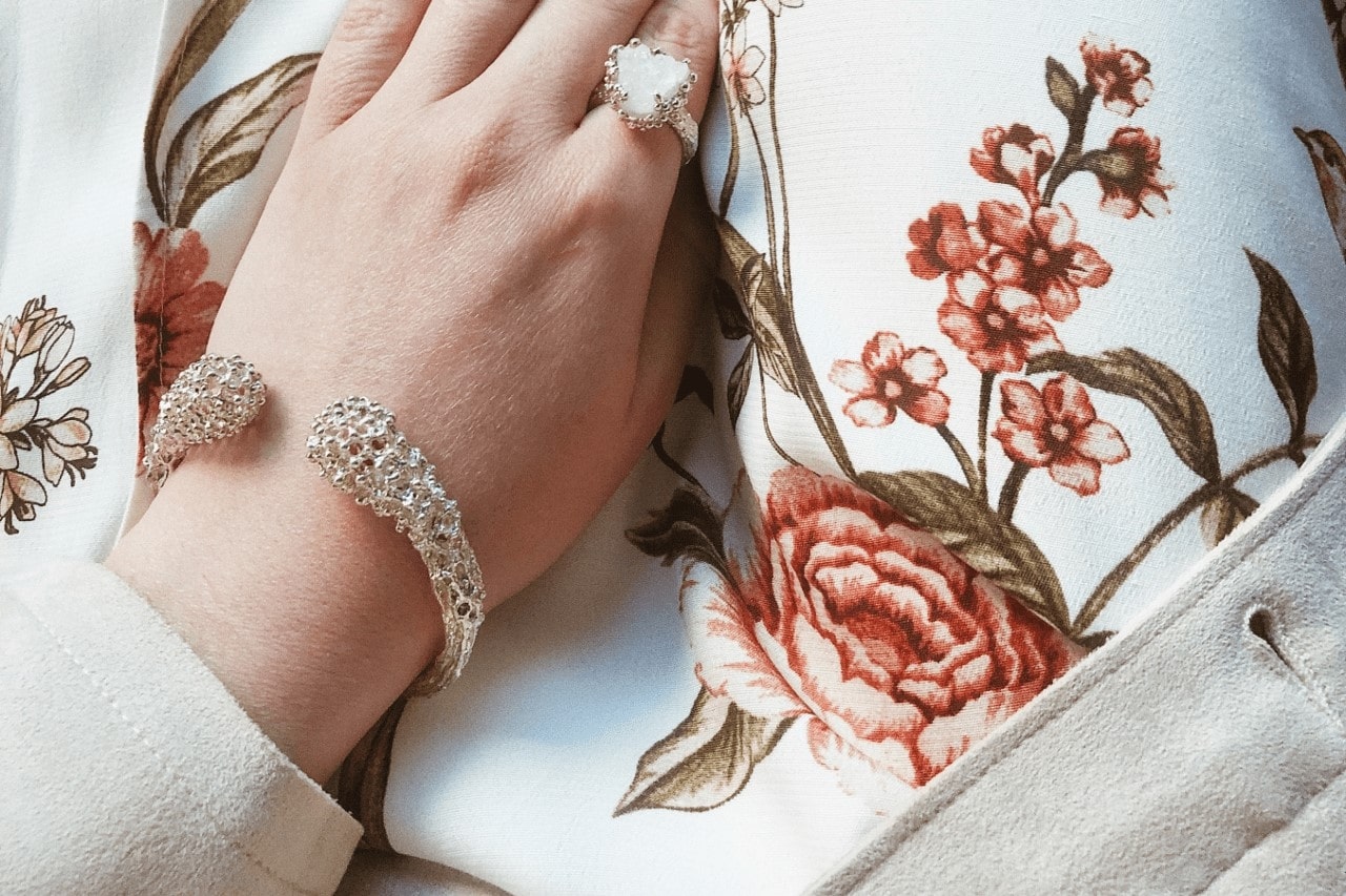 a lady’s hand wearing a platinum bracelet and fashion ring