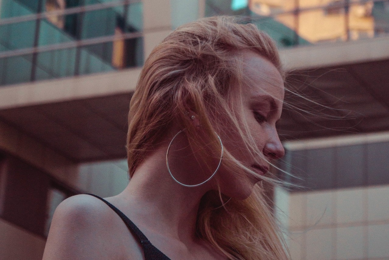 a lady looking to the side wearing large, white gold hoop earrings