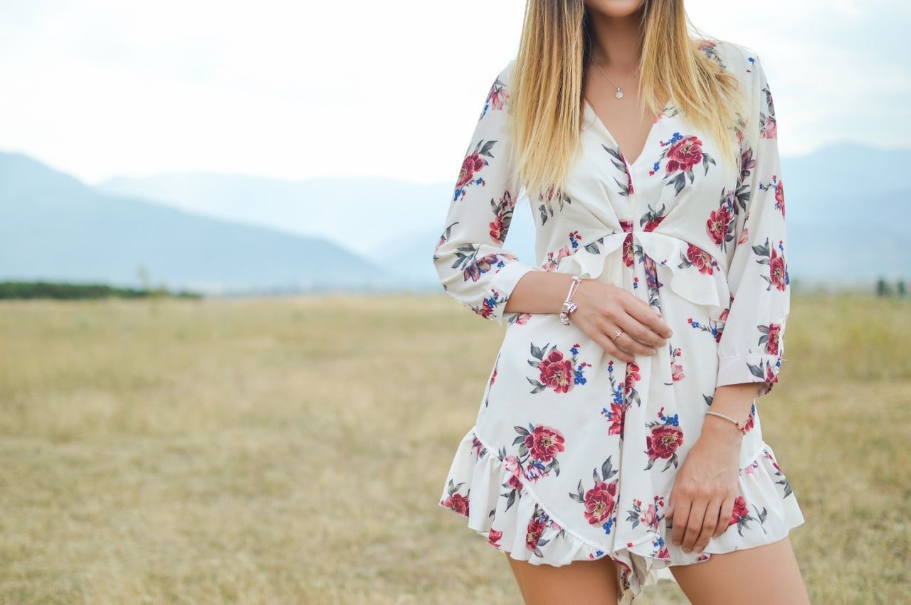 a lady standing in a meadow and wearing white gold jewelry