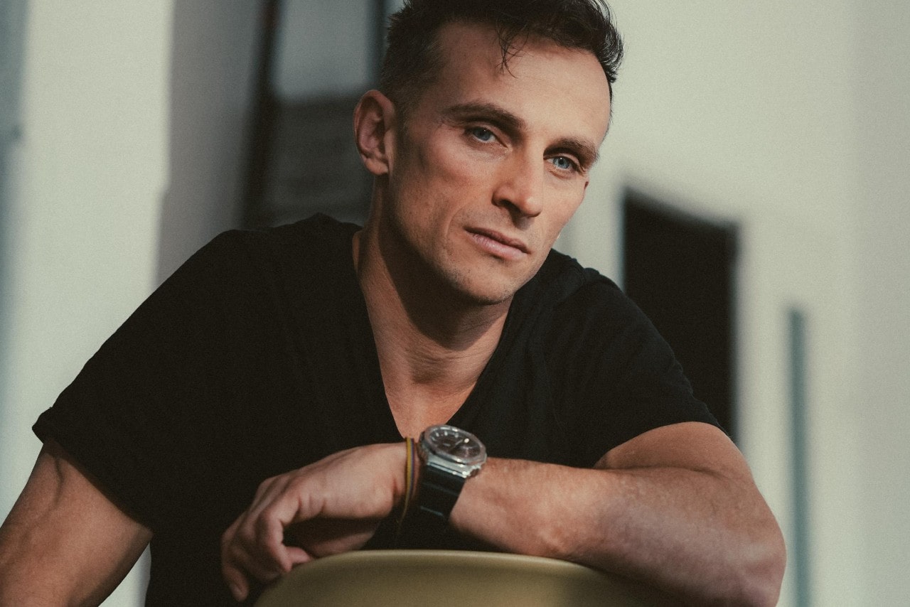 a man sitting backwards in a chair wearing a black and silver watch