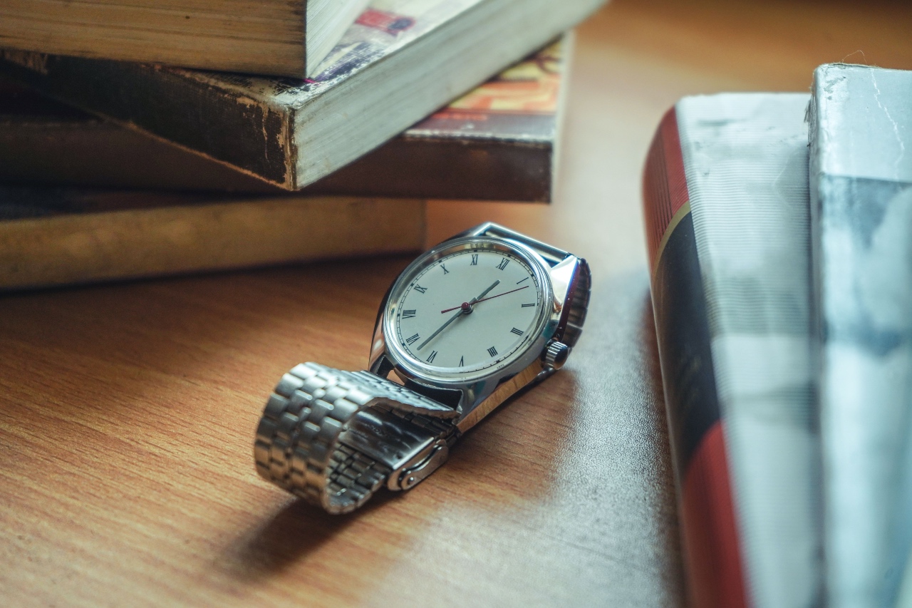 A close-up of a luxury watch in a wooden desk surrounded by books.