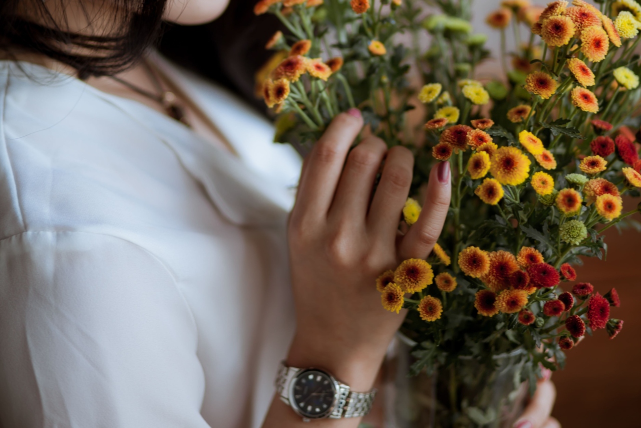 An close up of a woman in a white shirt holding a bouquet with a stainless steel watch on her hand