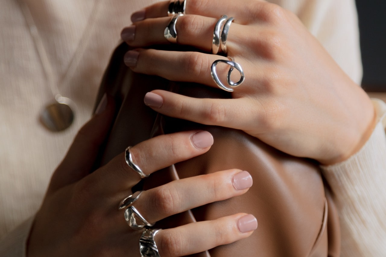 A woman wears a variety of silver rings.