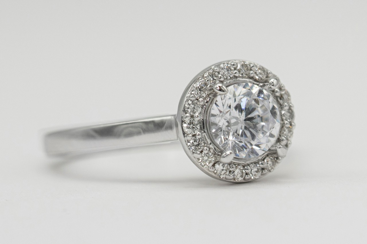 A platinum halo engagement ring with a round cut center diamond.