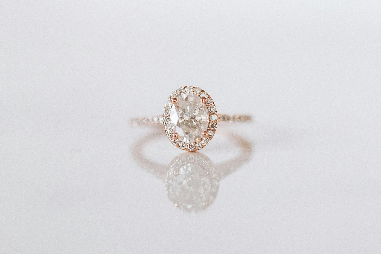 A rose gold halo engagement ring with an oval cut center stone.