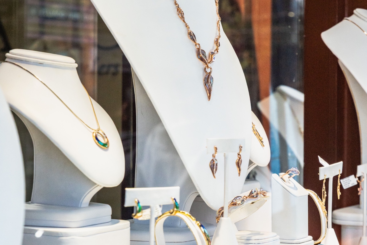 A storefront display window showcasing bronze leaf-shaped necklaces, earrings, and bracelets arranged on white leather display busts.