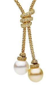A lariat necklace features two pearls with diamond accents and a gold popcorn chain.