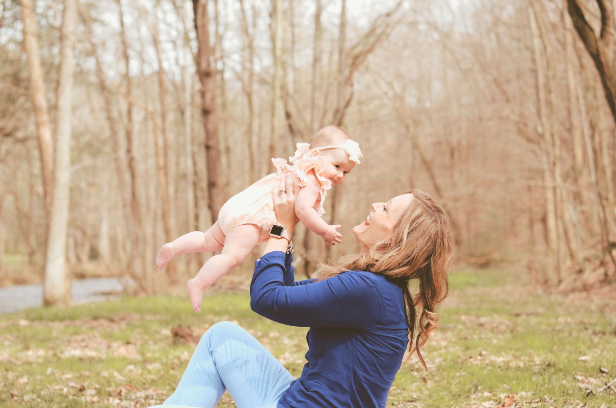 A woman plays with her baby girl in a park.