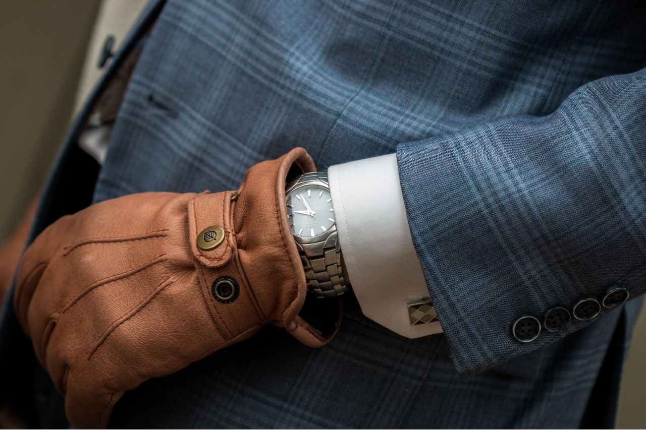 A businessman wearing leather gloves sports a watch.