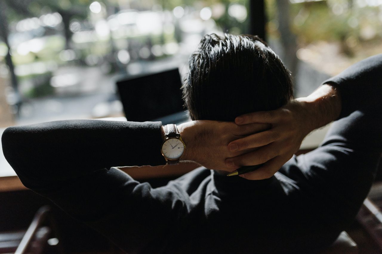 A man sits back and enjoys the city view out of his office window.