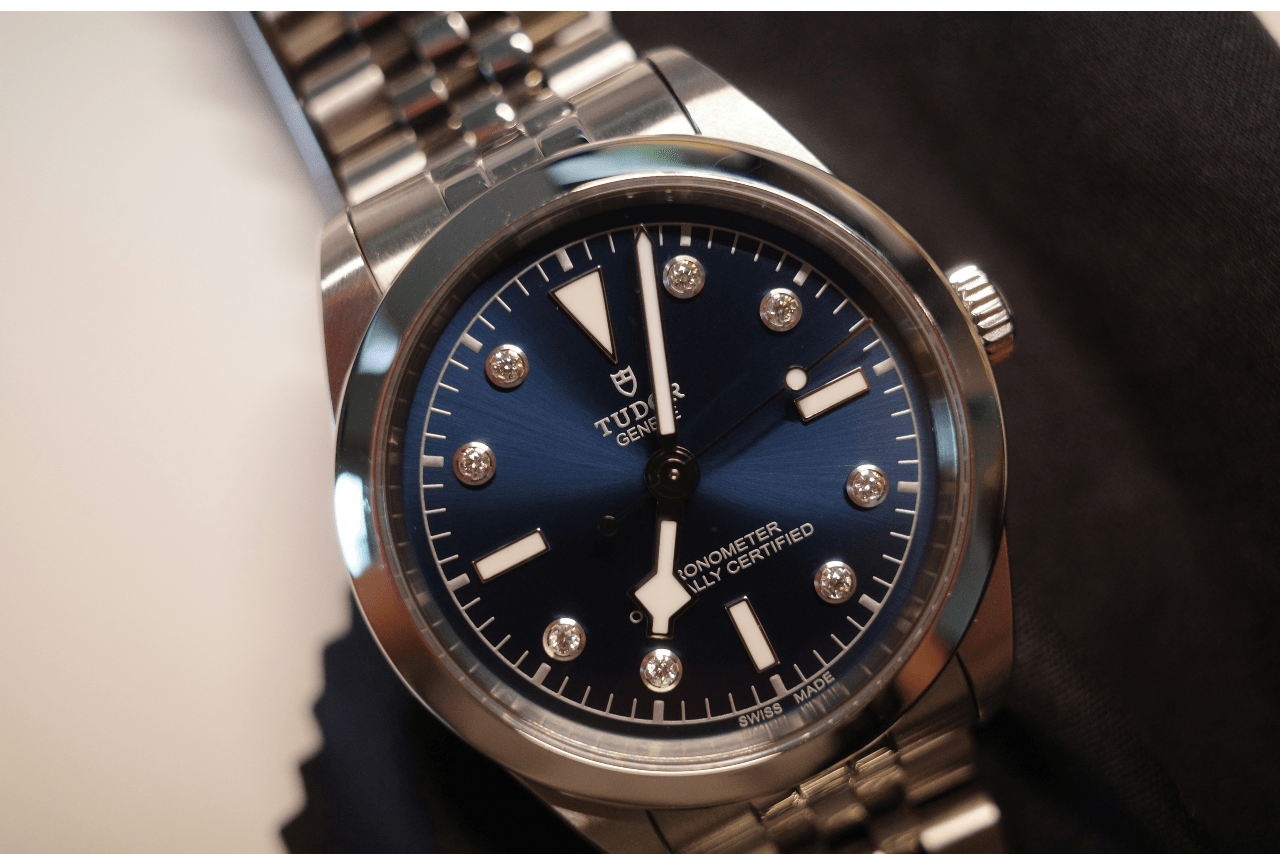 A close-up of an elegant TUDOR watch with diamond details on its dial.