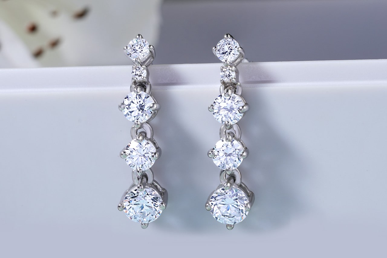 a pair of four-tiered, round cut diamond earrings in a silver setting