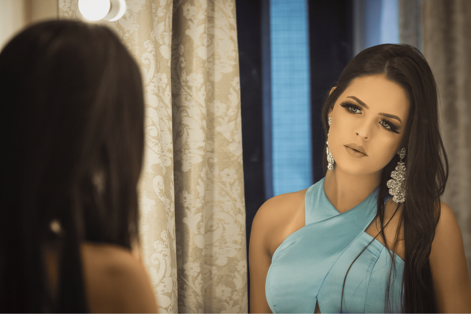 lady in front of a mirror wearing glamorous earrings