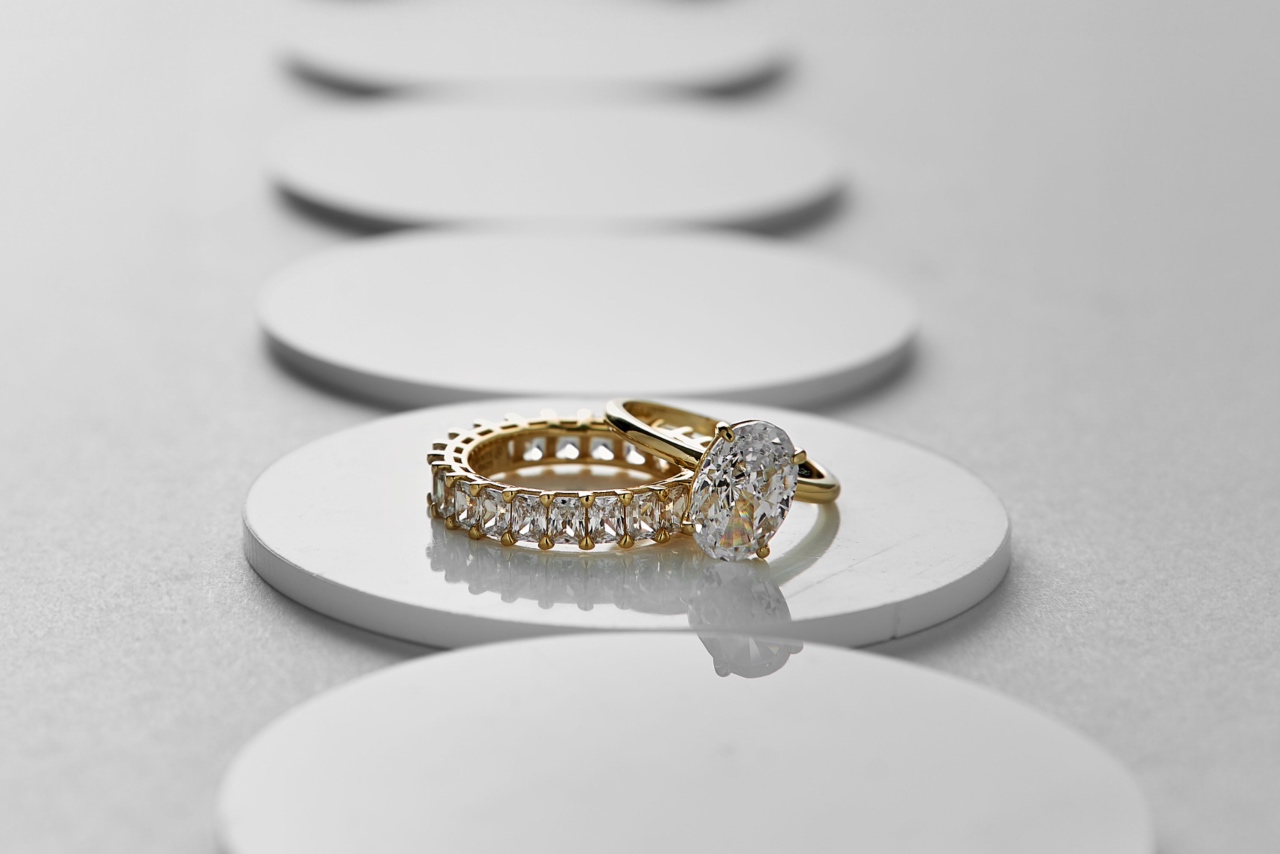 An eternity diamond wedding ring with a matching yellow gold solitaire diamond ring on a white reflective surface.