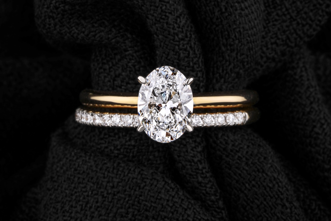A wedding ring set, showcasing a yellow gold engagement ring and a diamond-encrusted wedding band with an oval cut diamond.
