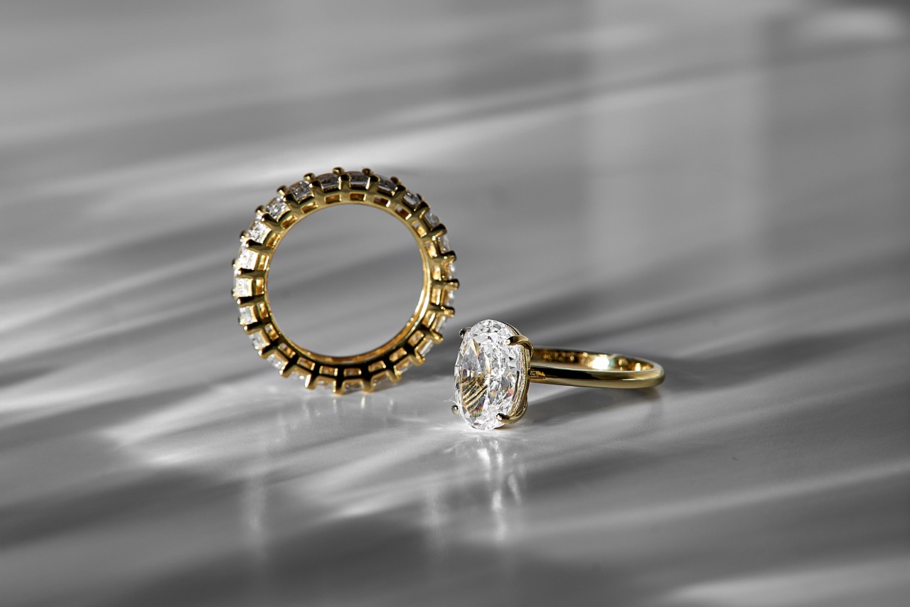 An eternity diamond wedding ring with a matching yellow gold solitaire oval-cut diamond ring on a white surface.