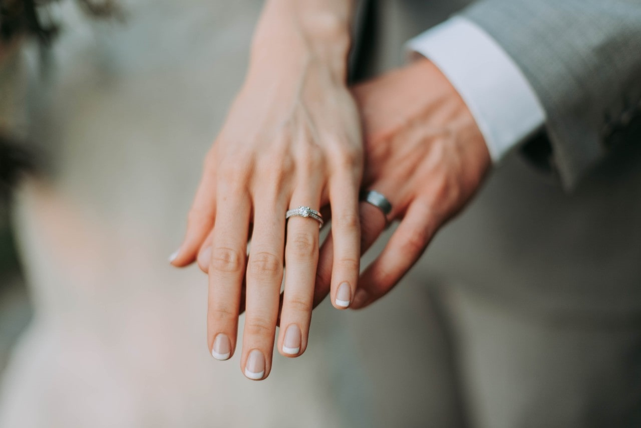 bride and groom holding hands and displaying wedding bands