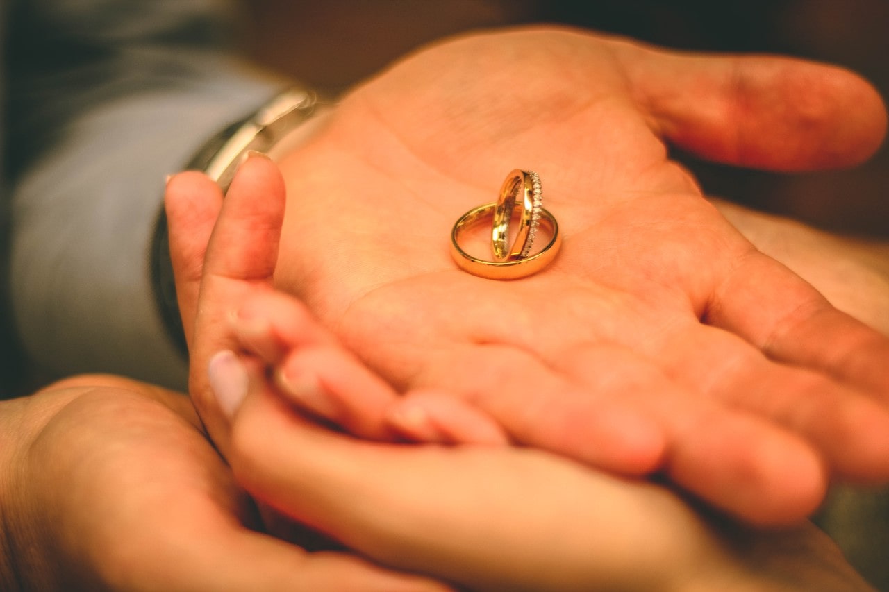 A close up of a person’s palm with two yellow gold wedding bands.