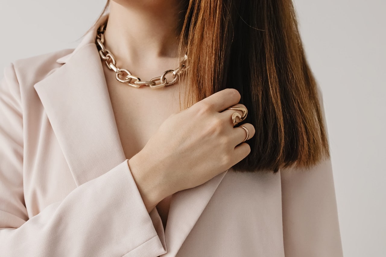 A woman wearing a blazer paired with yellow gold jewelry.