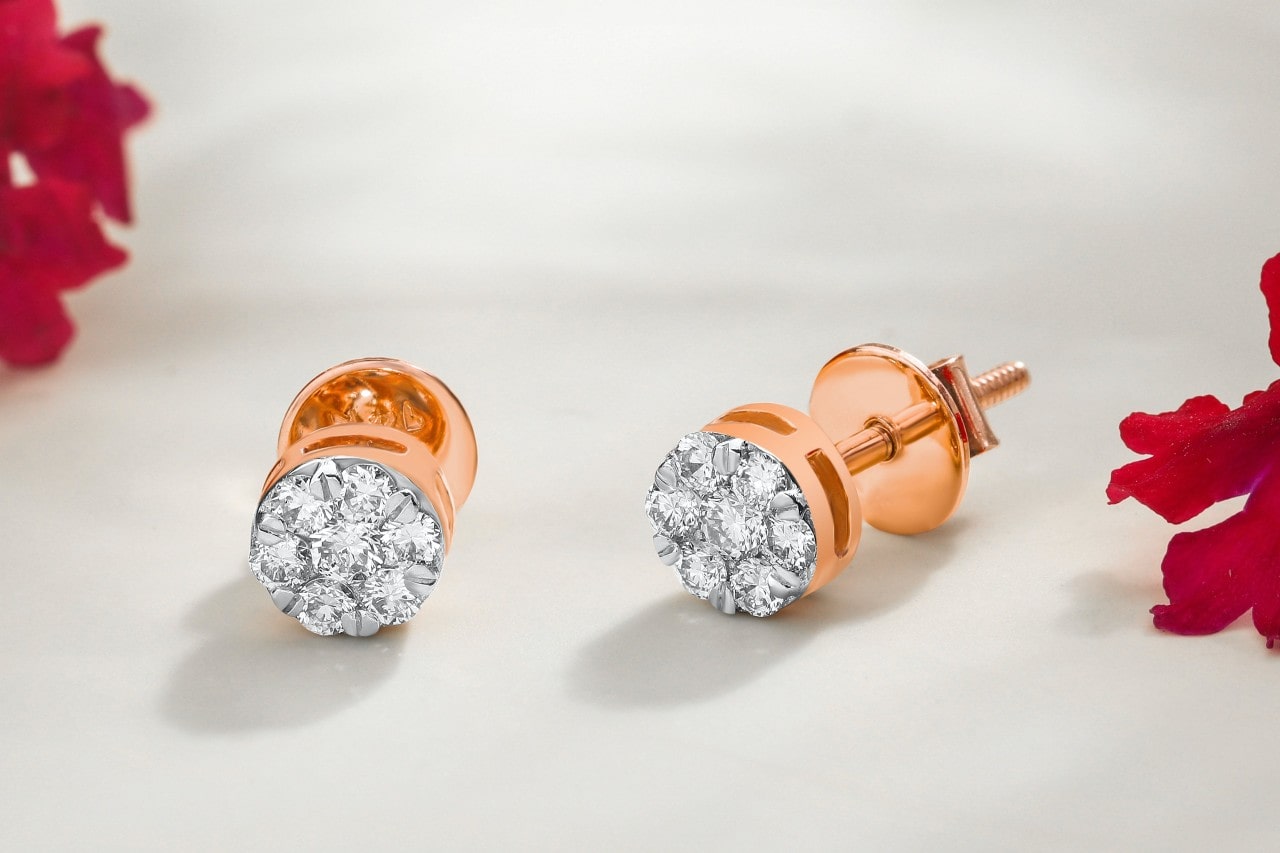 A rose gold round diamond studs on a white background with red flowers. A rose gold round diamond studs on a white background with red flowers.