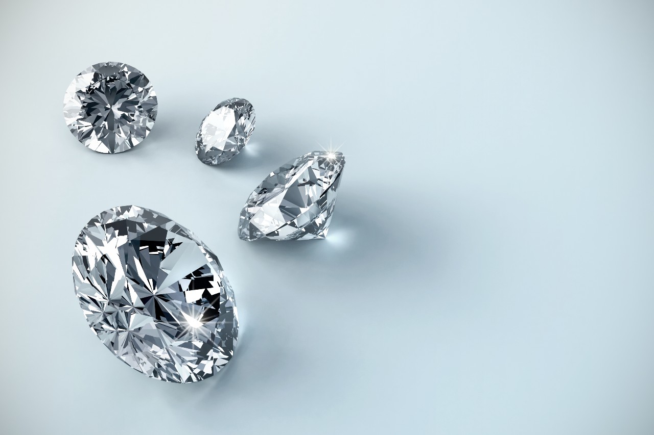 Four round-cut diamonds arranged on a light surface.
