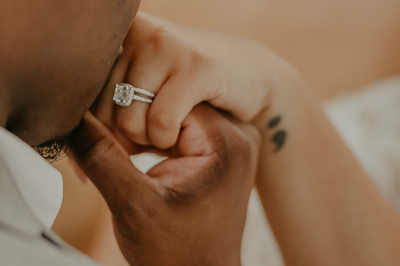 a man kissing a woman’s hand wearing an engagement ring with pave setting