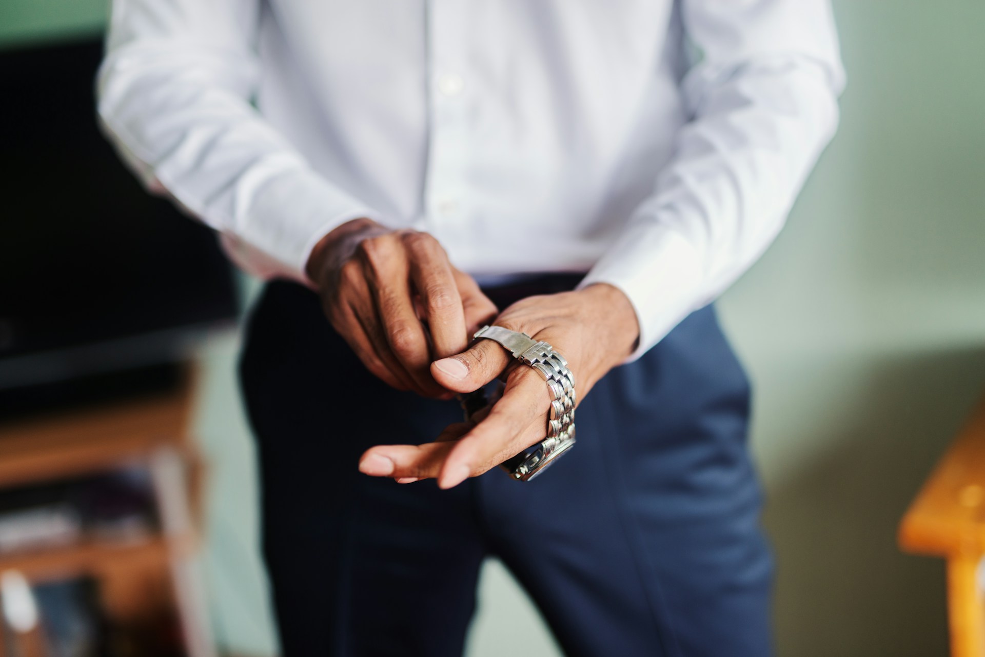 A close up of a man in white shirt and blue pants wearing a watch.